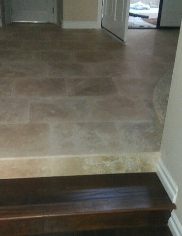 hardwood staircase leading to a tiled hallway