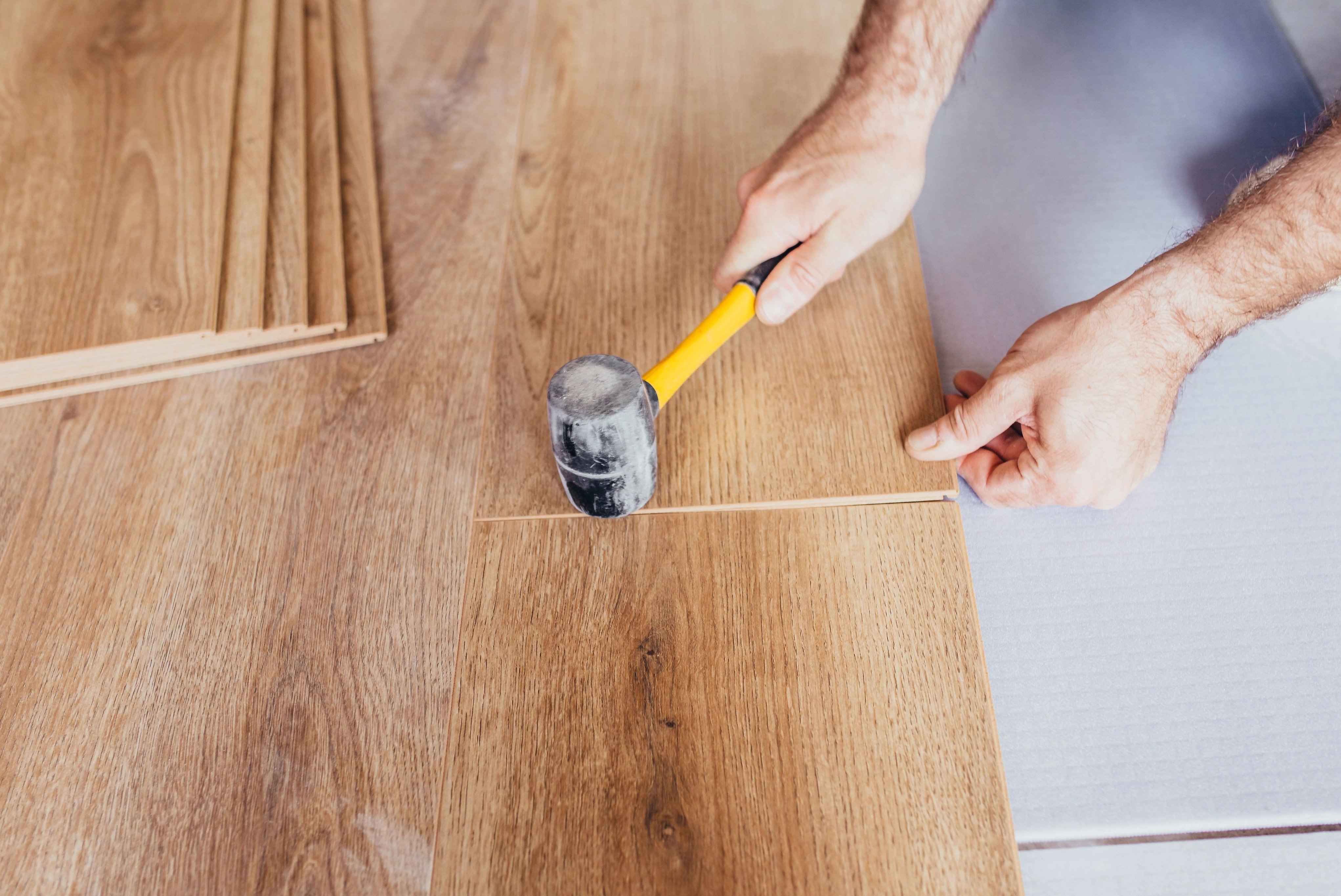 person installing flooring provided by Kenny's Custom Flooring Inc. in San Marcos, CA