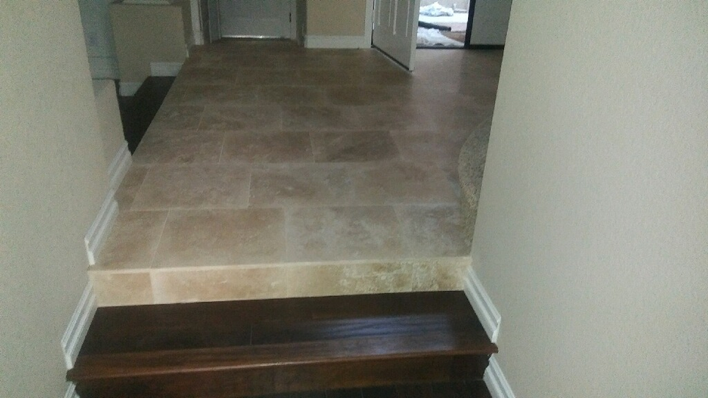 hardwood staircase leading to a tiled hallway